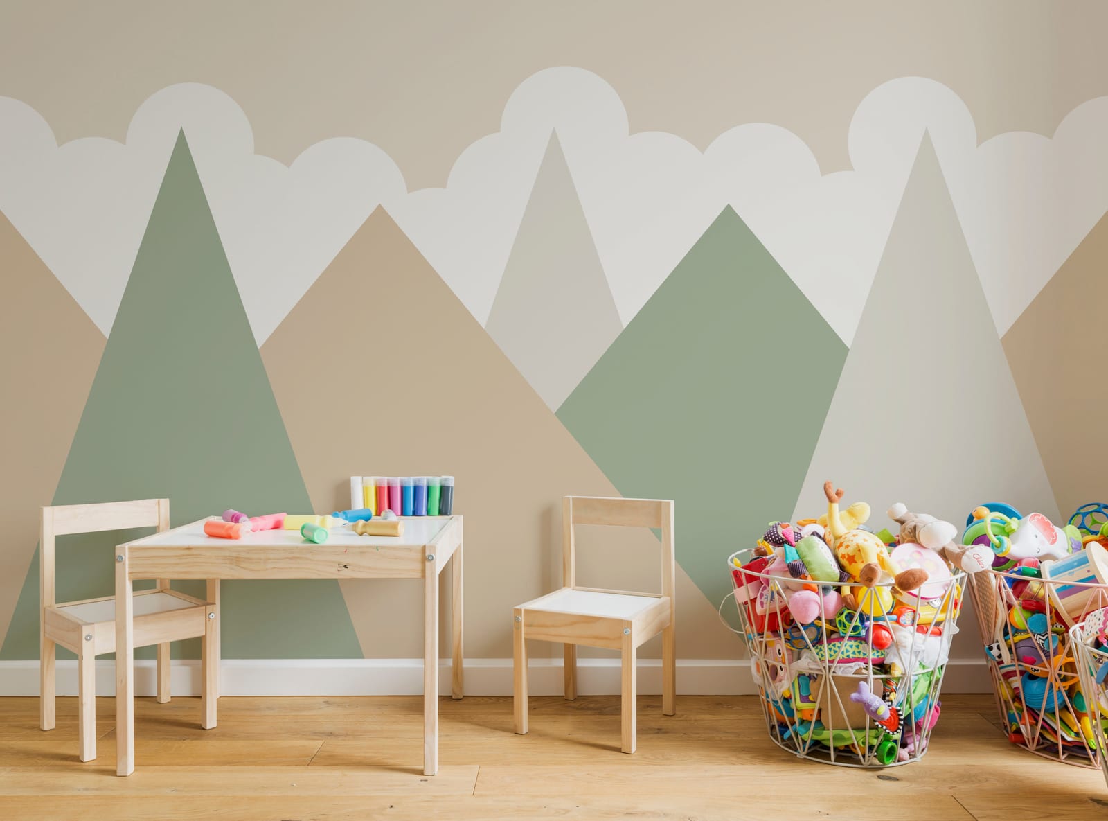 Modern kids nursery interior featuring pastel mountain wallpaper mural creating playful Scandinavian adventure theme.
